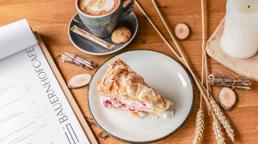 Stück Kuchen und ein Cappuccino und Kerze auf holztisch