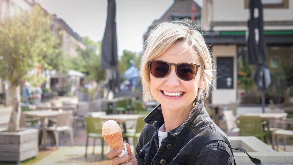 Frau lächelt mit Kugel Eis in der Hand