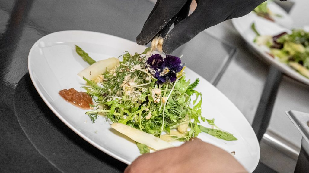 Koch streut Krokant auf Salat