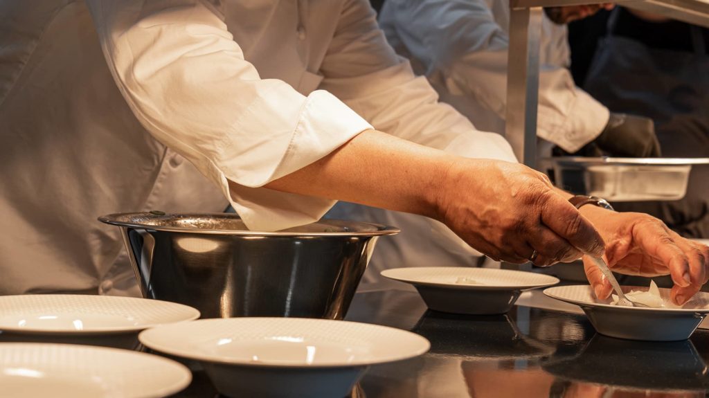 Koch hebt Spargel auf Teller