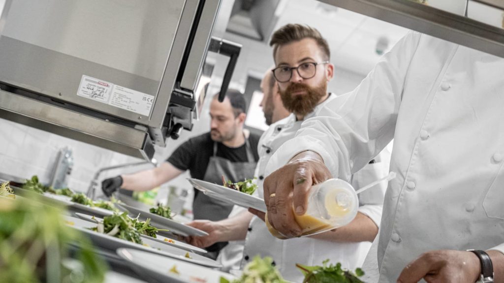 Köche richten Salate an mit Dressing