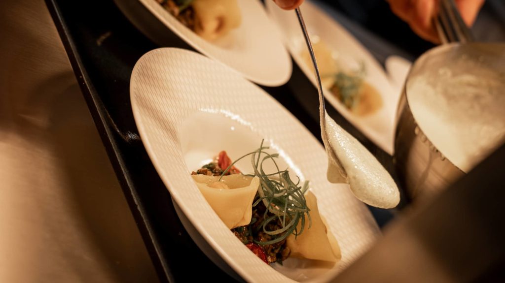 Löffel mit Schaum und Teller mit Tortellini