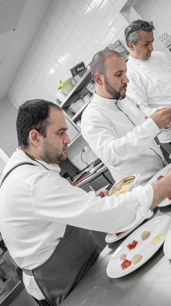 Drei Köche richten Dessert auf Tellern an